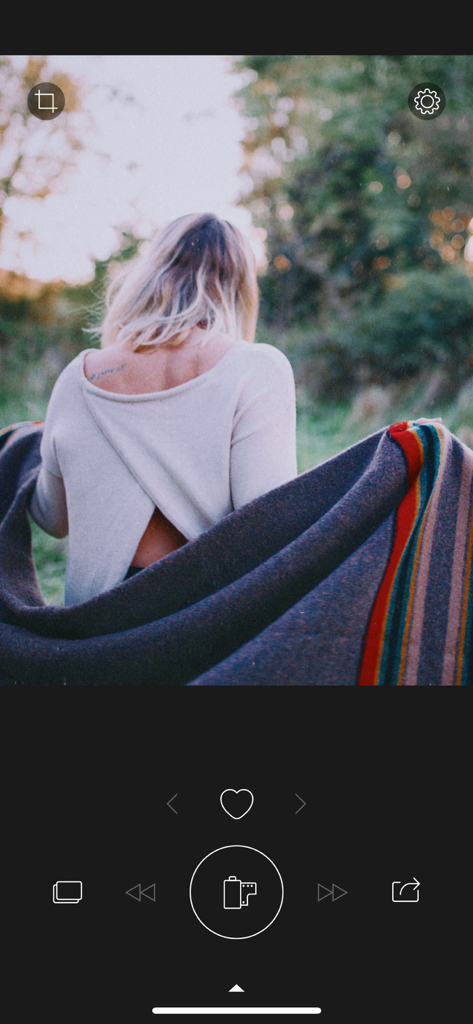 RNI Colibri app interface showing a nostalgic film-style photo of a woman wrapped in a blanket outdoors