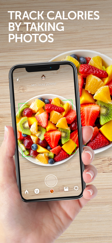 Una mano sosteniendo un smartphone usando la aplicación Calorie Mama AI para rastrear calorías sacando una foto de un tazón de frutas.