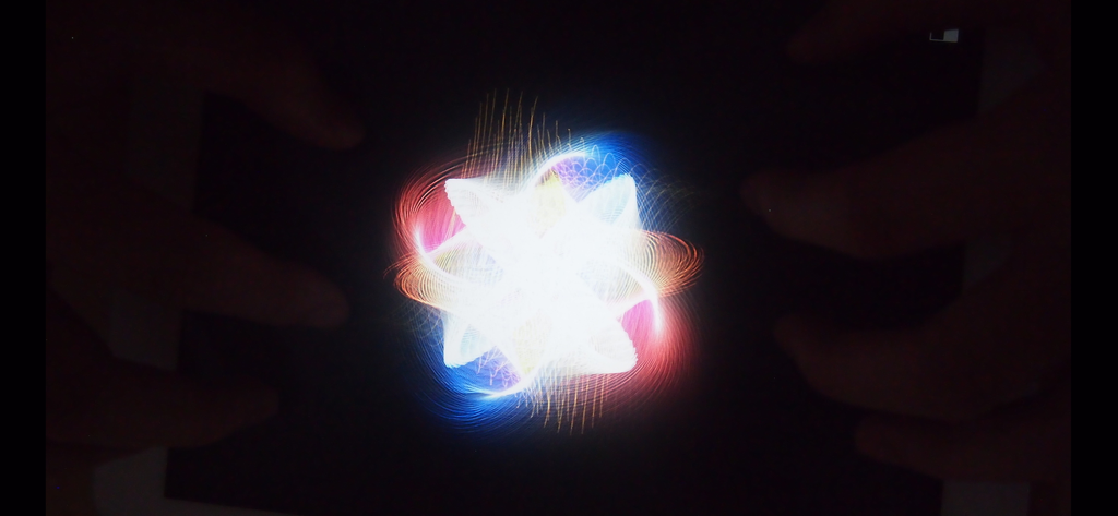 Una formazione di particelle al neon multicolore luminose su uno sfondo nero dall'app Atomus