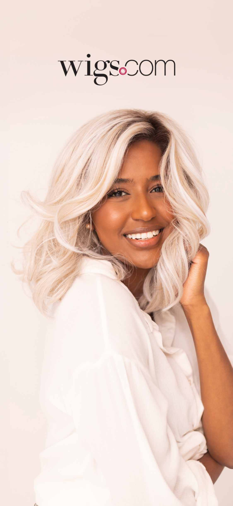 Wigs.com - Smiling woman wearing a stylish blonde wavy wig