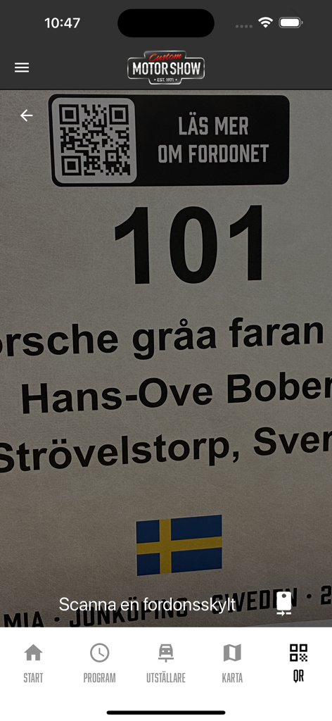 Custom Motor Show - カスタムモーターショーアプリのQRリーダーを使用して、車両展示プレートをスキャンして情報を取得しているモバイルデバイス。