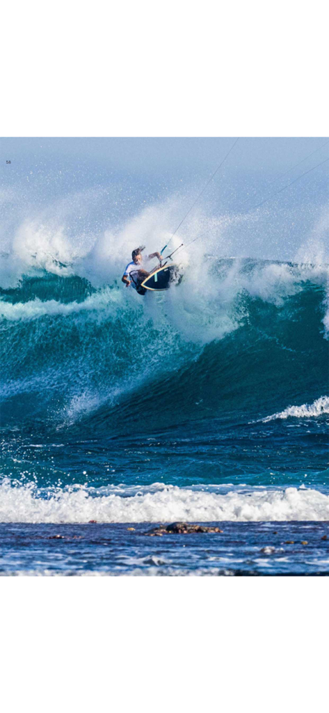 Un kitesurfista realizando un salto sobre una gran ola del océano rompiendo