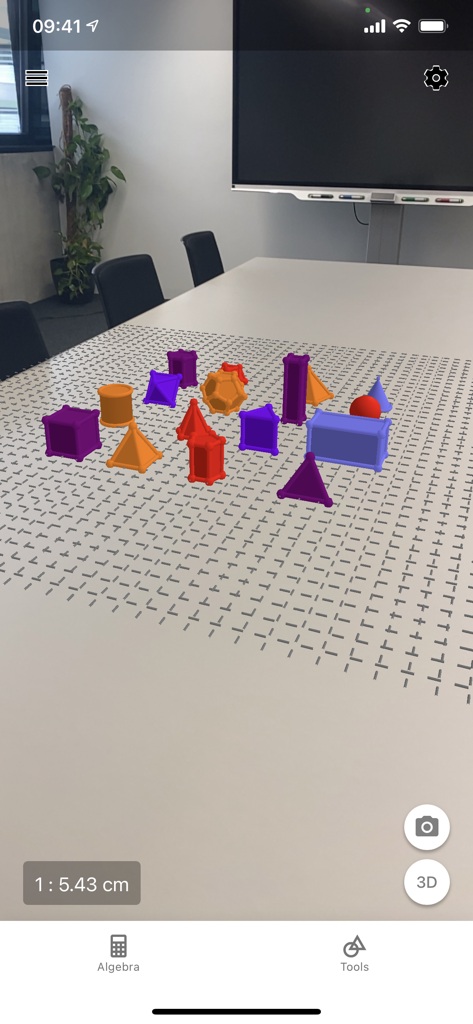 GeoGebra 3D Calculator - 흰색 테이블 위에 있는 다채로운 3D 기하학적 도형의 증강 현실 보기