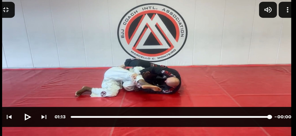 Dos practicantes de Jiu Jitsu Brasileño demostrando técnicas de agarre en tatamis rojos en un video tutorial