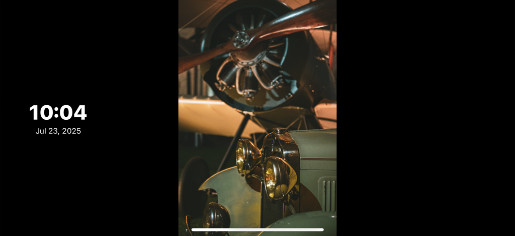 FotoSlide app displaying a vintage airplane and car photo with a minimal clock overlay