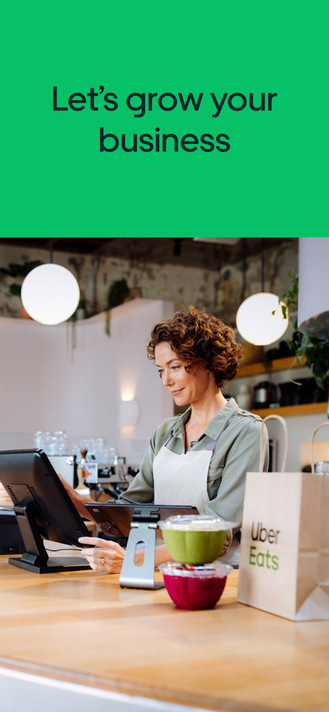 A restaurant manager using a tablet and POS system for Uber Eats orders at a counter