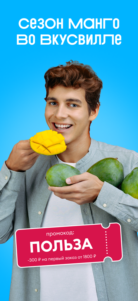 A man holding fresh mangoes featuring a promotional discount code for the VkusVill grocery app