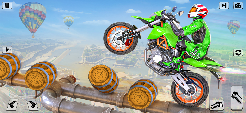 Una moto de acrobacias verde realizando un caballito sobre barriles de madera en una pista elevada con globos aerostáticos de fondo.