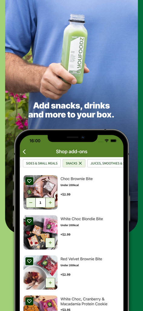 A person holding a green Youfoodz juice next to a smartphone showing healthy snack options like brownie bites in the app.