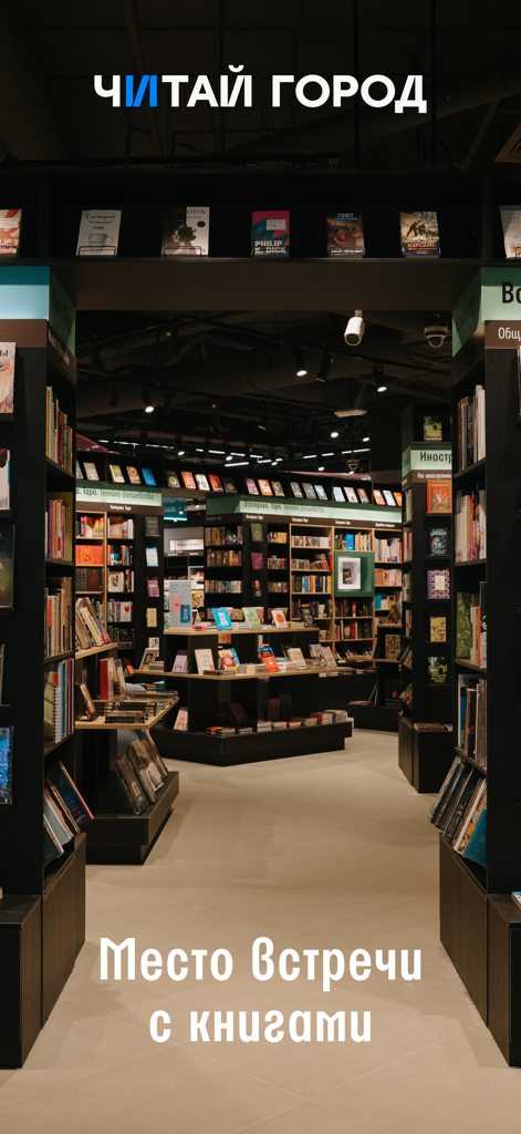 Читай-город: книжный магазин - Interior de una librería Chitai-Gorod con estanterías llenas de libros y texto ruso que dice "Meeting place with books"