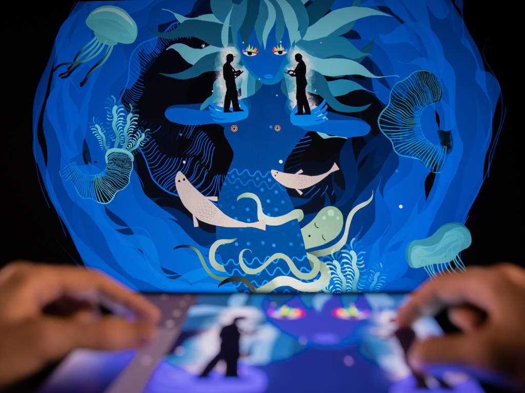 Una persona usando la aplicación Tagtool en un iPad para crear una ilustración digital proyectada en vivo de una escena submarina mítica.