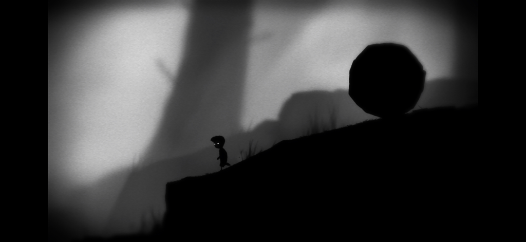 Playdead's LIMBO - Silueta de un niño con ojos brillantes caminando hacia una gran roca en un bosque oscuro y brumoso