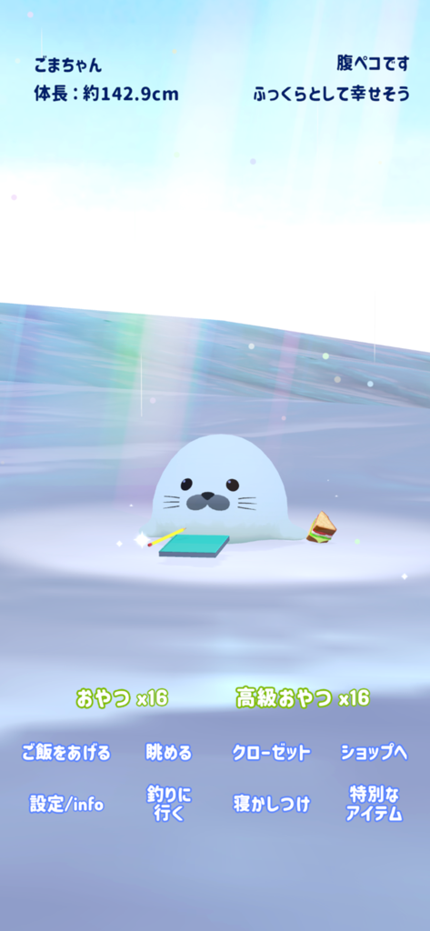 癒しのアザラシ育成 - A cute white baby seal sitting on ice with a sandwich and stationery in a mobile pet care game.
