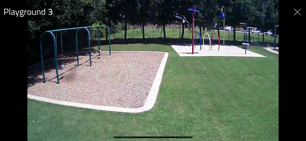 WatchMeGrow - WatchMeGrow app screen showing a live video feed of a childcare center playground with swings and play structures