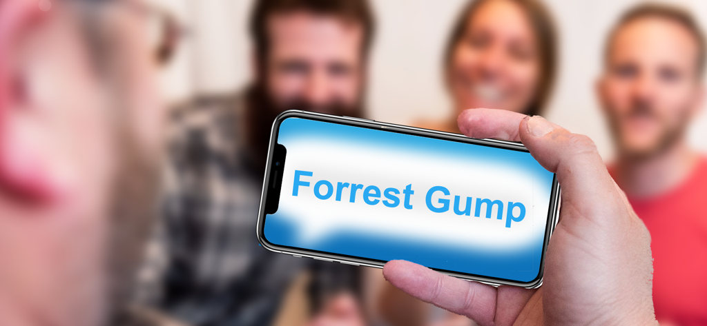 Phrase Party! — Guess Phrases - A group of friends playing Phrase Party with a phone displaying the phrase Forrest Gump