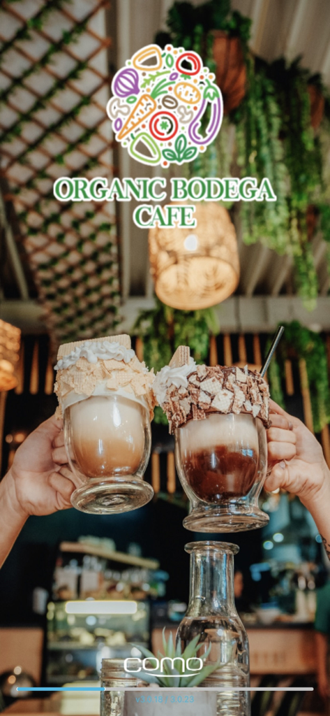 Organic Bodega Cafe - Organic Bodega Cafe app welcome screen featuring two hands holding decorative specialty lattes in a cozy plant-filled interior.