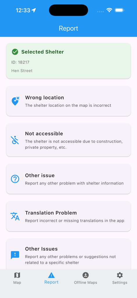 Reporting screen in the Bomb Shelter Locator app showing options to report wrong location, accessibility issues, or translation problems for a specific shelter.