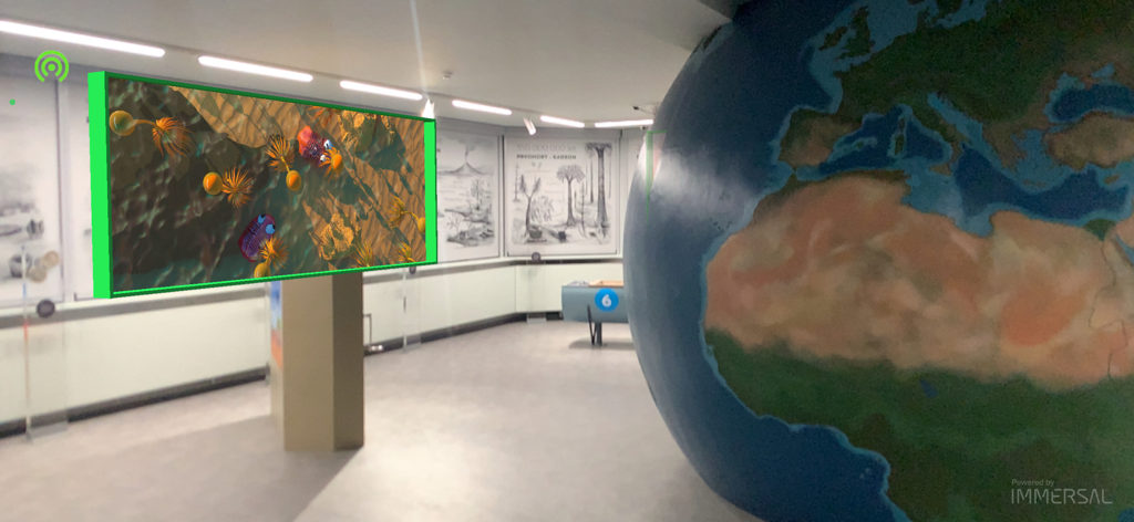 Augmented reality display of prehistoric sea creatures in a museum gallery next to a large globe