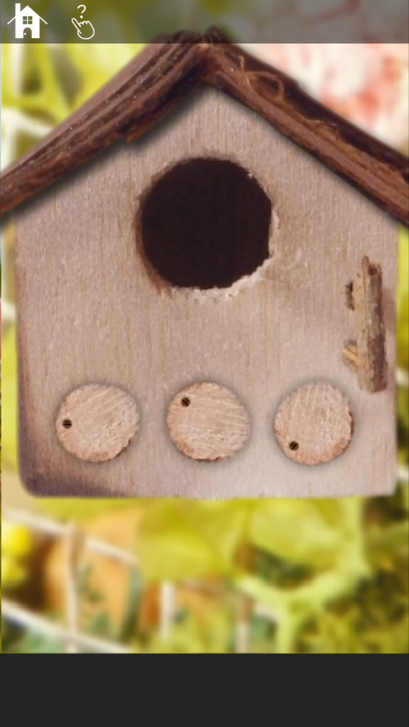 Escape game: MiniatureLAND - A close up view of a wooden birdhouse puzzle with circular dials in a peaceful miniature garden setting