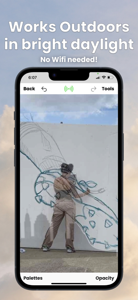 Mural Maker by Da Vinci Eye - A person using the Mural Maker app to paint a large mural outdoors in bright daylight with AR guidance