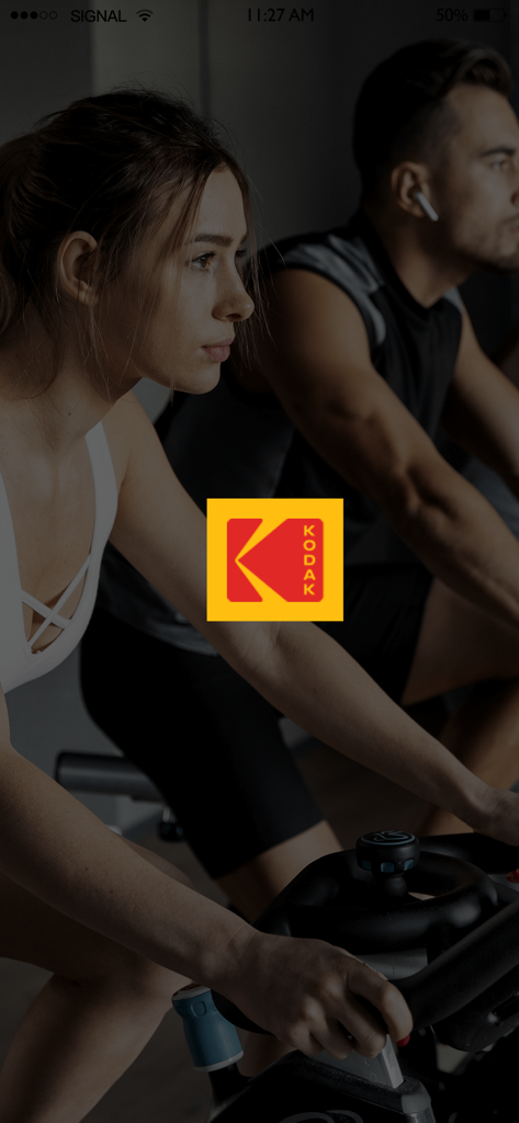 KODAK SMART WATCH - Écran de démarrage de l'application Kodak Smart Watch montrant un homme et une femme sur des vélos d'appartement avec le logo Kodak au centre