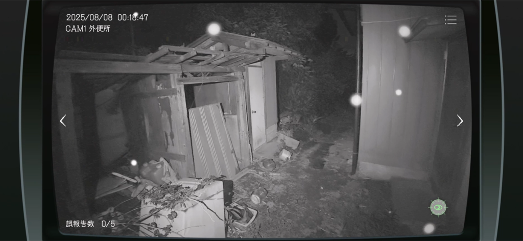 Japan Stigmatized Property - 暗い屋外の小屋の浮遊する白いオーブを映した、グレインのある暗視セキュリティカメラ映像。