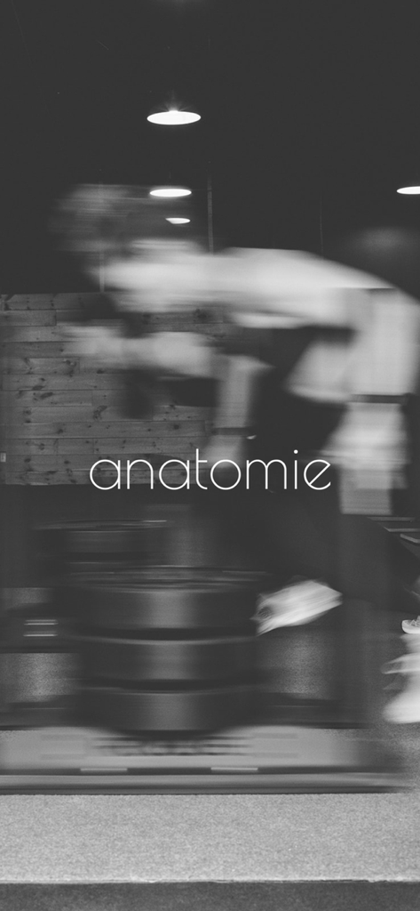 Black and white motion blurred image of a person exercising in a gym with the Anatomie studio logo