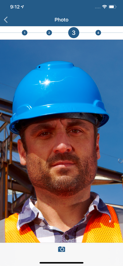 A construction worker in a safety vest and hard hat taking a biometric verification photo in the ExakTime app.