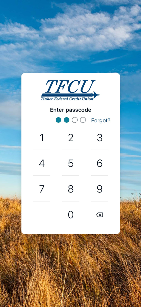 Tinker Federal Credit Union mobile app passcode entry screen with a numeric keypad and scenic landscape background.