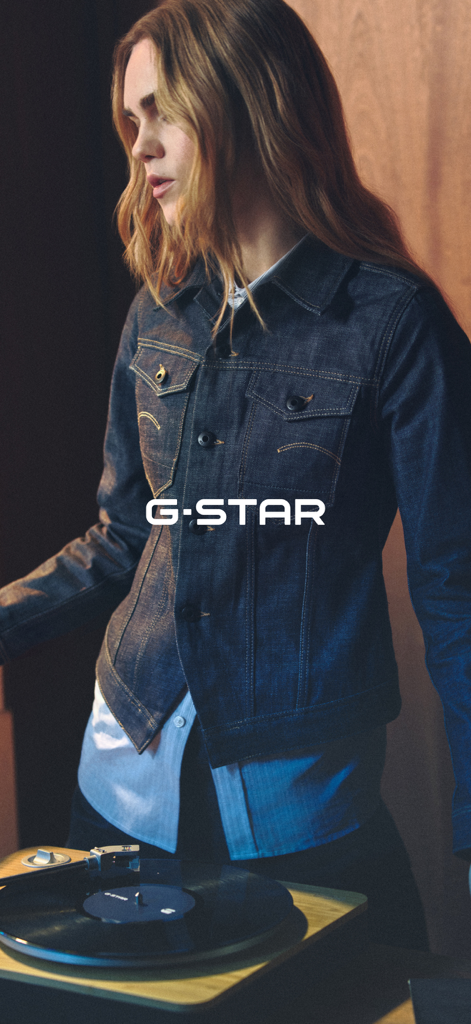Une femme portant une veste en denim G-Star premium se tenant à côté d'une platine vinyle