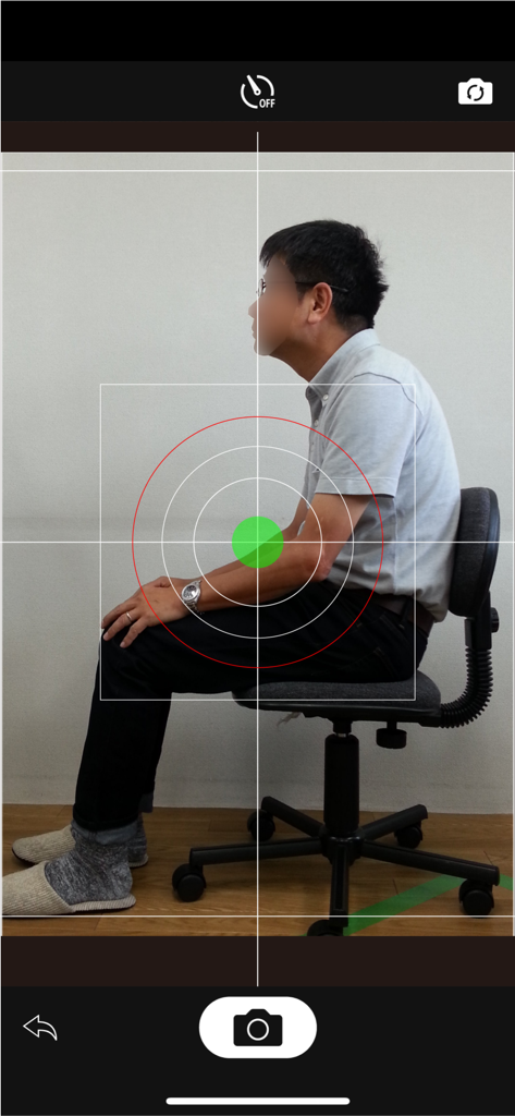 SittingPostureCHECKER - plus - A person sitting in an office chair captured through the SittingPostureCHECKER app with a built-in spirit level.