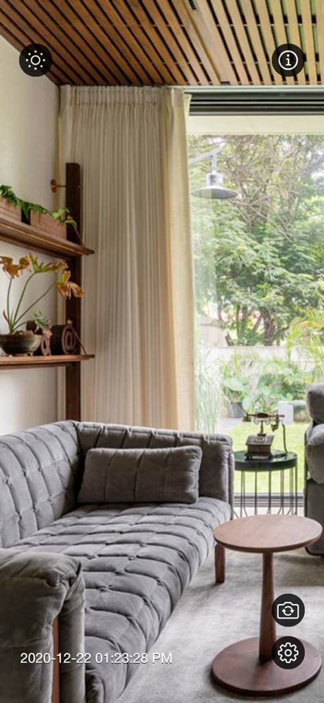 Interface of the Motion Detector Camera app showing a live surveillance view of a living room with a timestamp and controls.