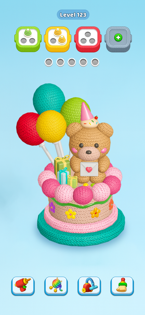 A colorful knitted birthday cake with a teddy bear in the sorting puzzle game Knit Away.