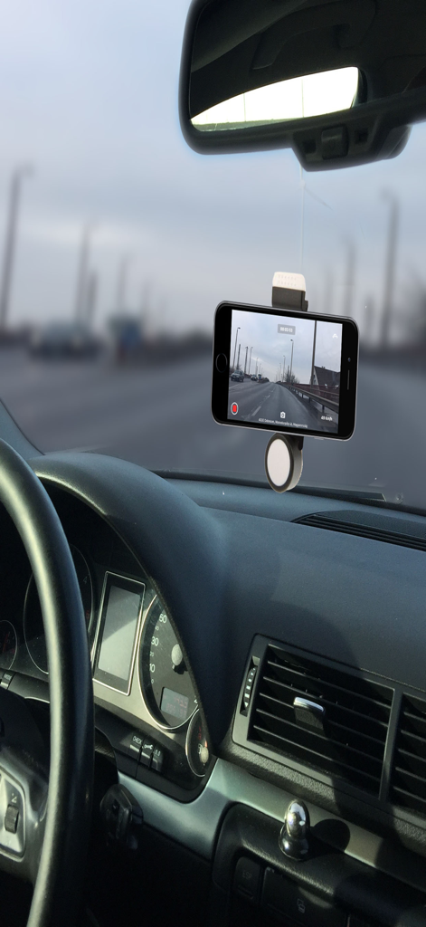 An iPhone mounted in a car using a dashcam app to record the road with speed and GPS data overlays