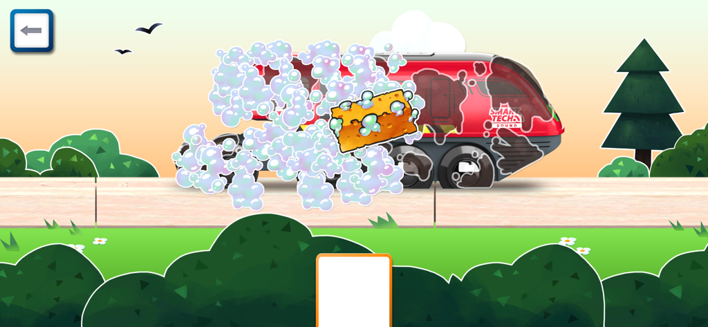 A red BRIO toy engine being cleaned with a yellow sponge and soap bubbles on a wooden track.