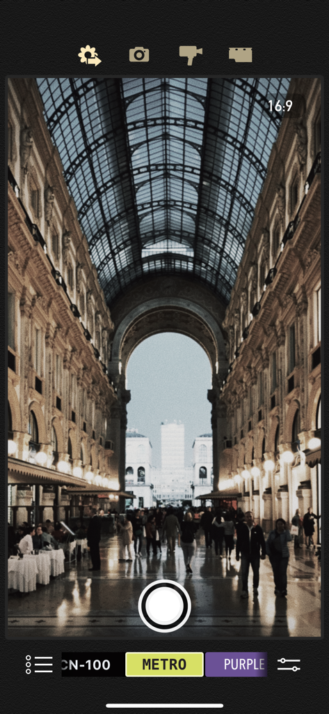 Una captura de pantalla de la interfaz de la aplicación Cámara Vintage de 8mm mostrando un gran salón arquitectónico a través de un filtro de película retro.