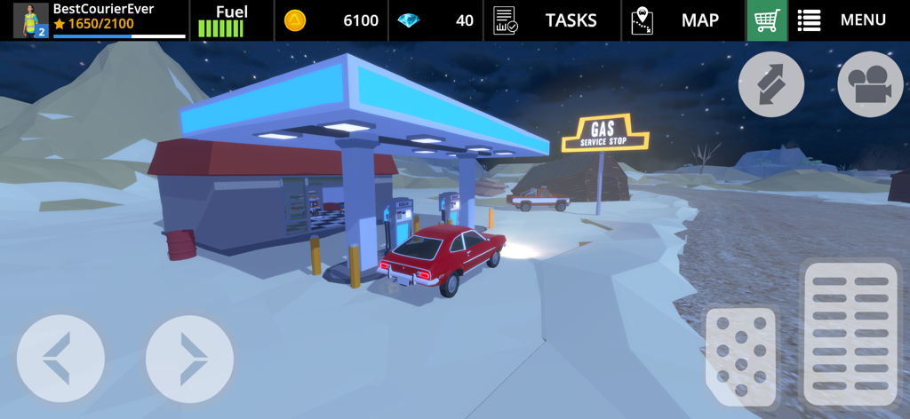 Un coche rojo aparcado en una gasolinera en un entorno de montaña nevada por la noche