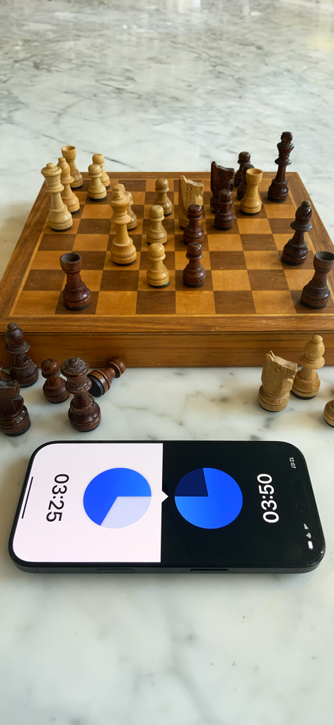 Chess Timer - A smartphone with a chess timer app placed next to a wooden chessboard with pieces