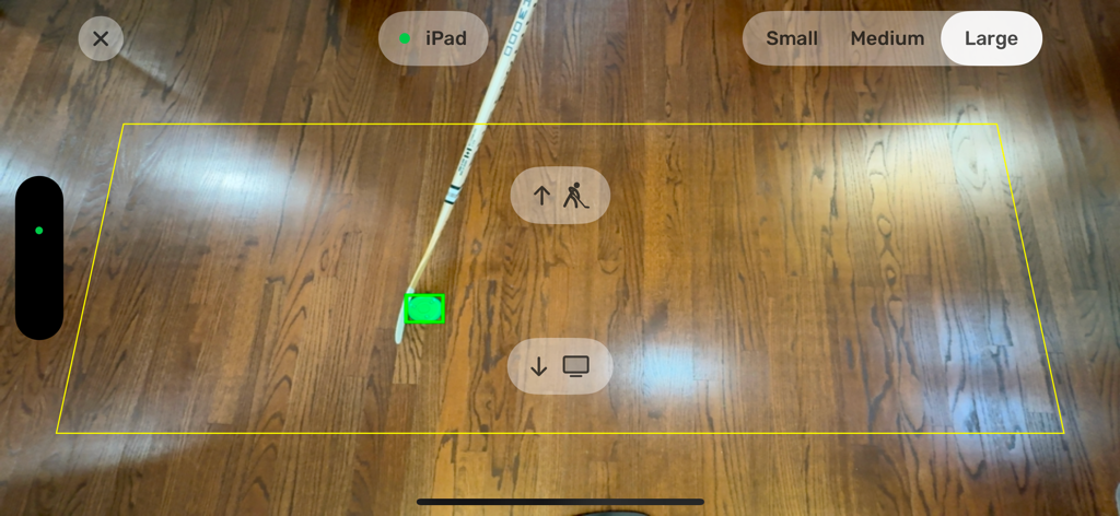 Dangleverse - Augmented reality view of the Dangleverse app tracking a hockey puck on a wooden floor using a hockey stick within a yellow bounding box.