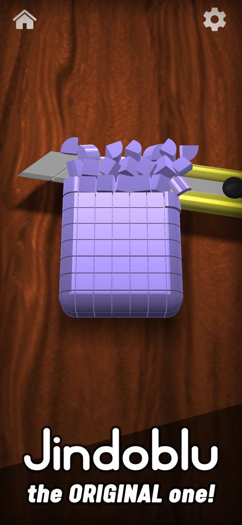 A purple block being sliced into small cubes by a utility knife on a wooden surface in the Antistress game.