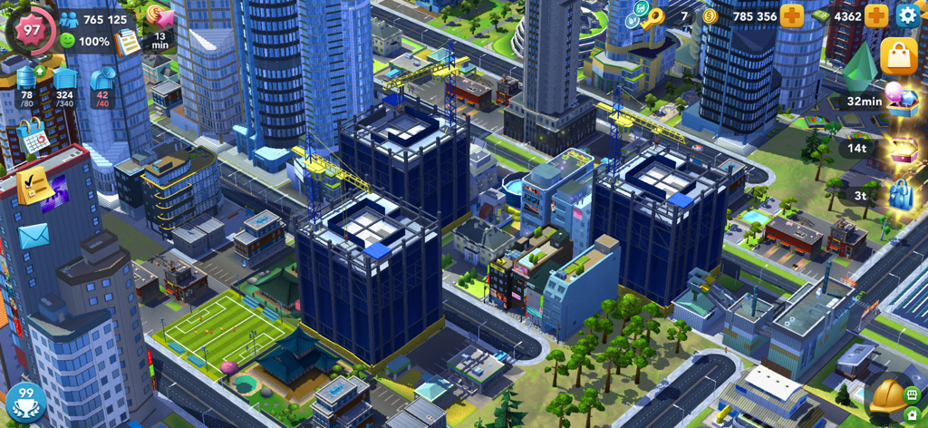 SimCity BuildIt - Una vivace disposizione cittadina in SimCity BuildIt con grattacieli in costruzione con gru e un campo da calcio verde
