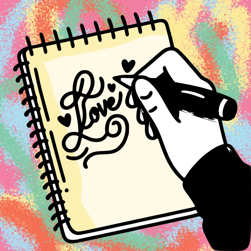 a hand writing “love” in calligraphy on a notebook