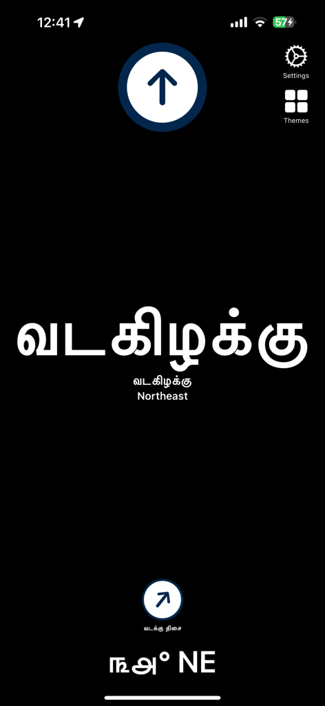 A smartphone screenshot of the Tamil Directions Compass app displaying the northeast direction in large Tamil characters on a dark background