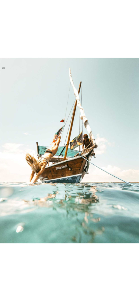 Mujer buceando desde un barco de madera tradicional en agua azul clara