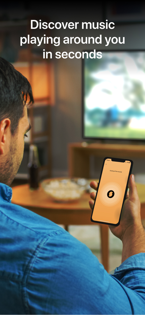 SoundHound∞ - Music Discovery - 男性がスマートフォンでSoundHoundアプリを使用し、テレビで流れている音楽を特定している様子