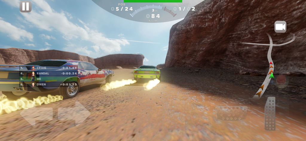 In-game view of two muscle cars racing on a dusty dirt track between red rock canyons.
