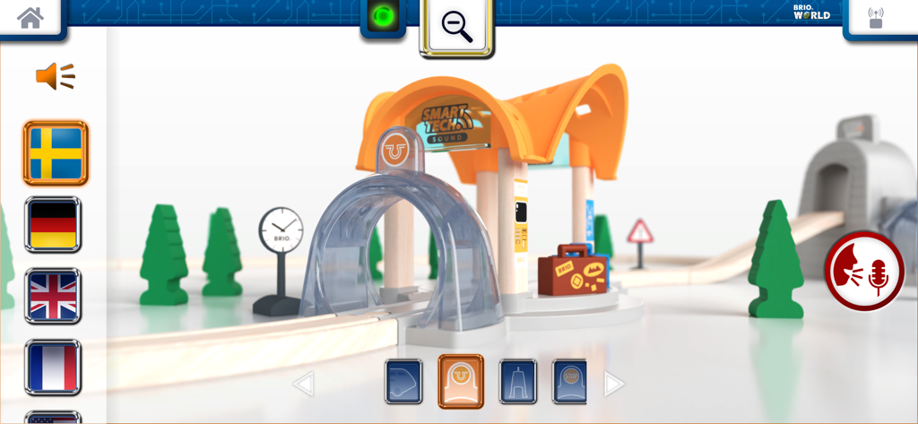 Interface of the BRIO Smart Tech Sound app showing a 3D toy train station with language selection flags and a voice recording icon