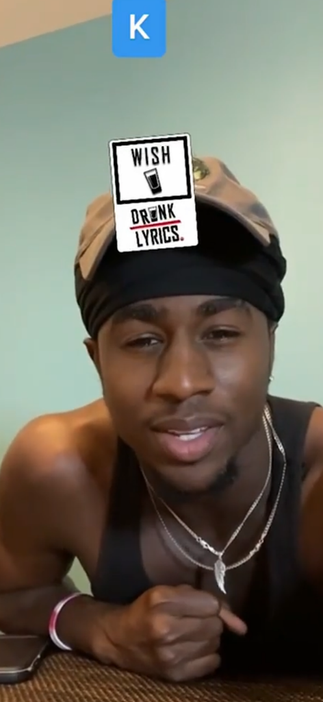 A man playing the Drunk Lyrics game with a card on his forehead showing the word Wish