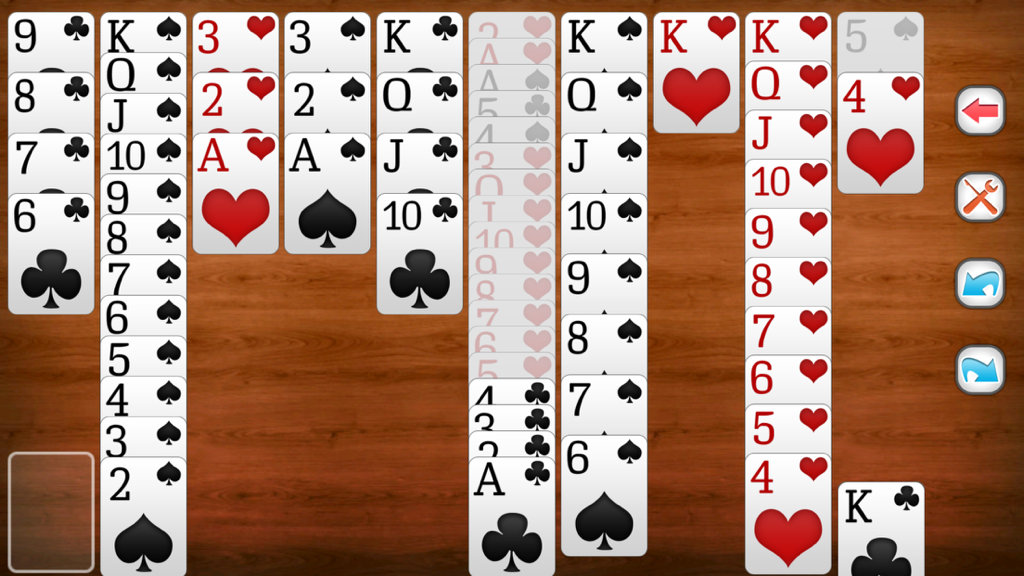 A game of Spider Solitaire showing card stacks on a wooden background