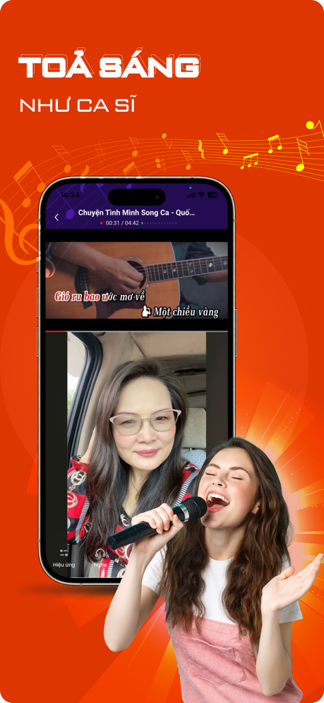 A woman singing into a microphone using the Yokara karaoke recording app with a phone interface in the background.